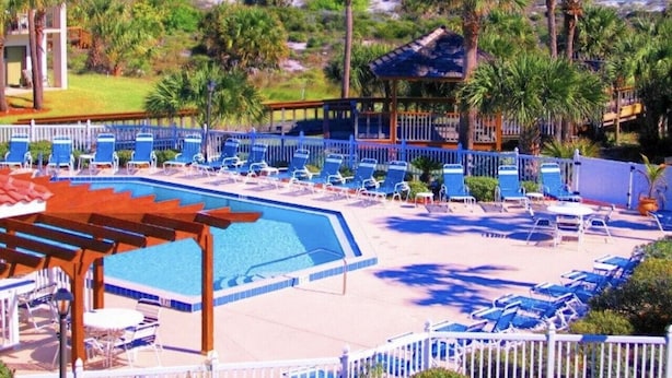 A pool area with lounge chairs and a view of the ocean.