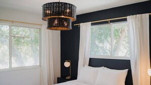 Un dormitorio con una cama grande, dos mesitas de noche, una lámpara de pie y una lámpara colgante.