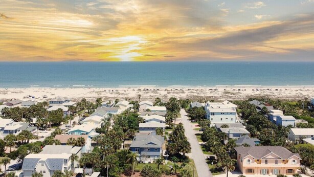 Zona residencial costera con casas y una playa al fondo.