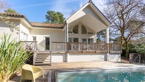 Ein zweistöckiges Haus mit überdachter Veranda und Schwimmbecken.