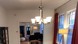A dining area with a long wooden table, chairs, a chandelier, and a window with curtains. - Historic Oak Park Home (Oak Park)