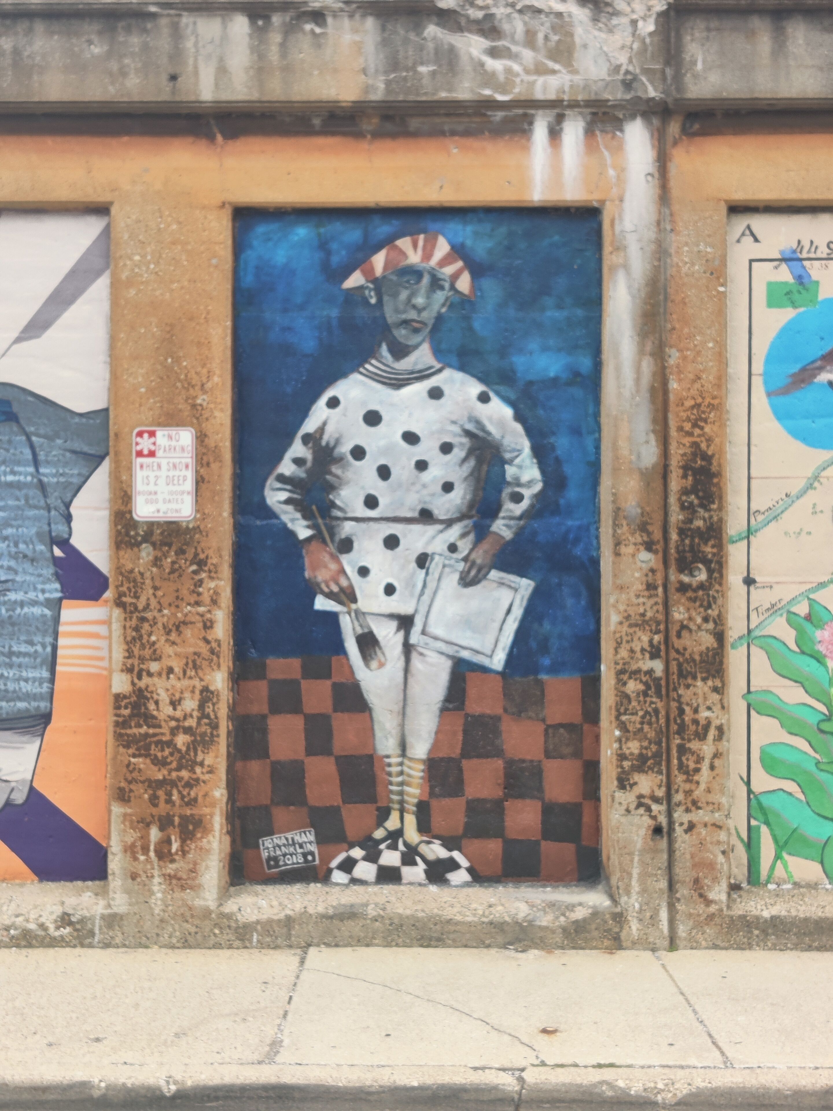 A mural of a figure in a polka-dotted outfit with a checkered pattern at the bottom.