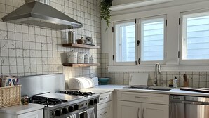 A modern kitchen with white cabinets, a stainless steel stove, and a large window. - Historic Oak Park Home (Oak Park)