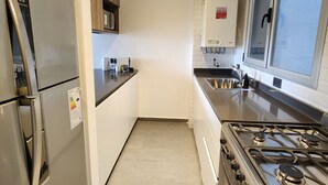 A modern kitchen with stainless steel appliances, a built-in oven, and a window providing natural light. - Loi Flats Neuquen, Edificio Talero (Neuquén)