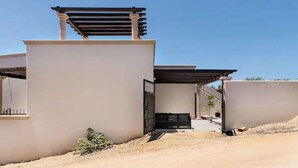 Un bâtiment moderne doté d’un toit plat, d’un patio couvert et d’un petit jardin.