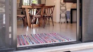 Un intérieur moderne avec un coin repas comprenant une table et des chaises en bois, un luminaire au plafond et un panneau d’accueil.