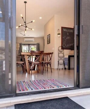 Enter a stylish dining area with a wooden table, comfortable chairs, and a welcoming chalkboard sign.