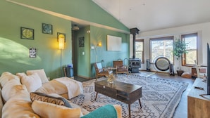 Un salon comprenant un canapé, des fauteuils, une table basse, une cheminée et un téléviseur.