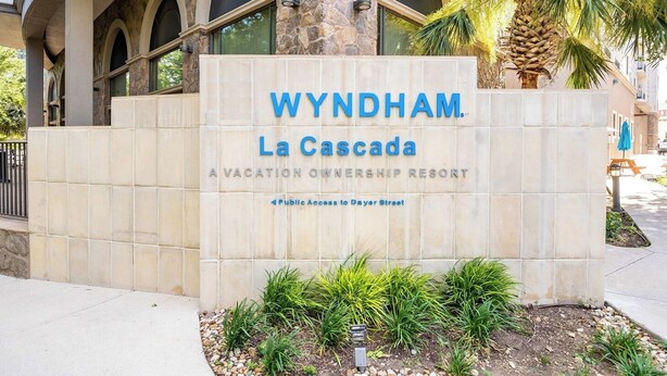 Señal de Wyndham La Cascada, un resort de propiedad vacacional, con fachada de piedra y ventanas arqueadas.