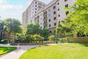 A multi-story residential building with balconies, surrounded by well-maintained greenery and a paved walkway. - San Antonio | Couples River Walk Getaway | Pool + Downtown (San Antonio)