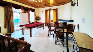 A billiards room with a pool table, chairs, and a ceiling fan. - Hotel Madhuvan (Kandaghat)