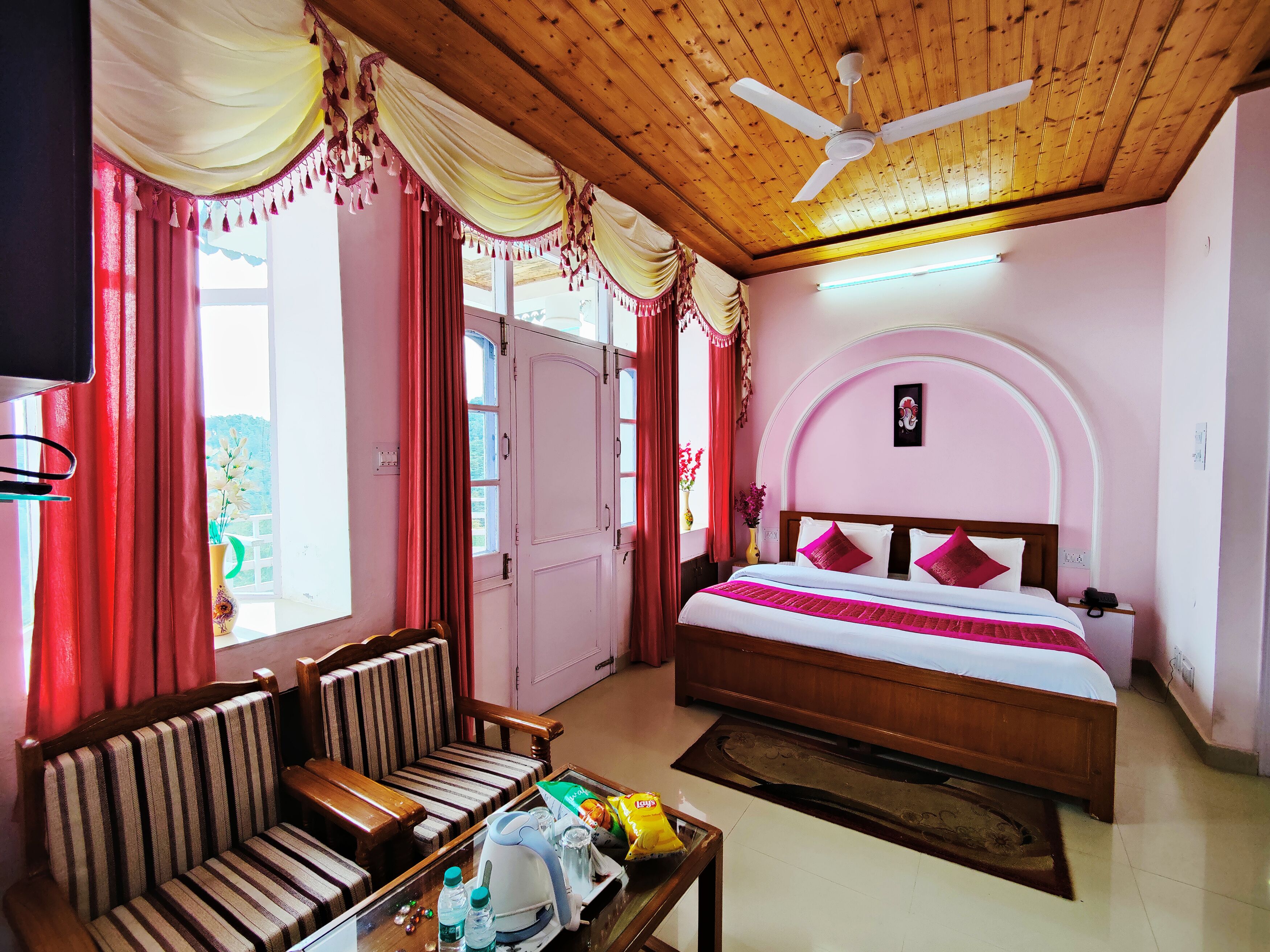 Una habitación de hotel con cama, sofá, mesa de centro y ventilador de techo.