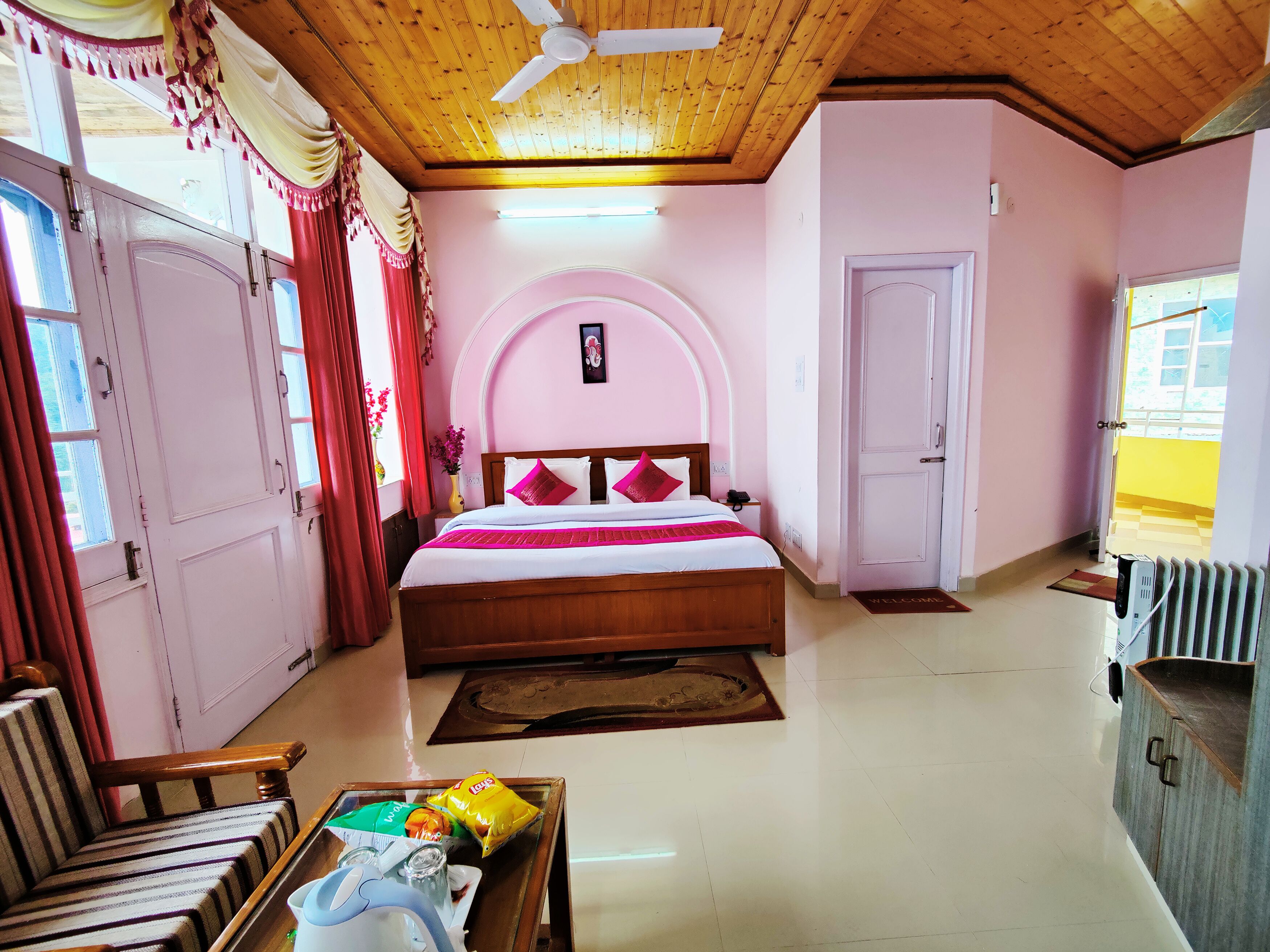 A bedroom with a bed, a wooden ceiling fan, a bedside table, a chair, and a radiator.