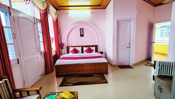 A bedroom with a bed, a wooden ceiling fan, a bedside table, a chair, and a radiator.