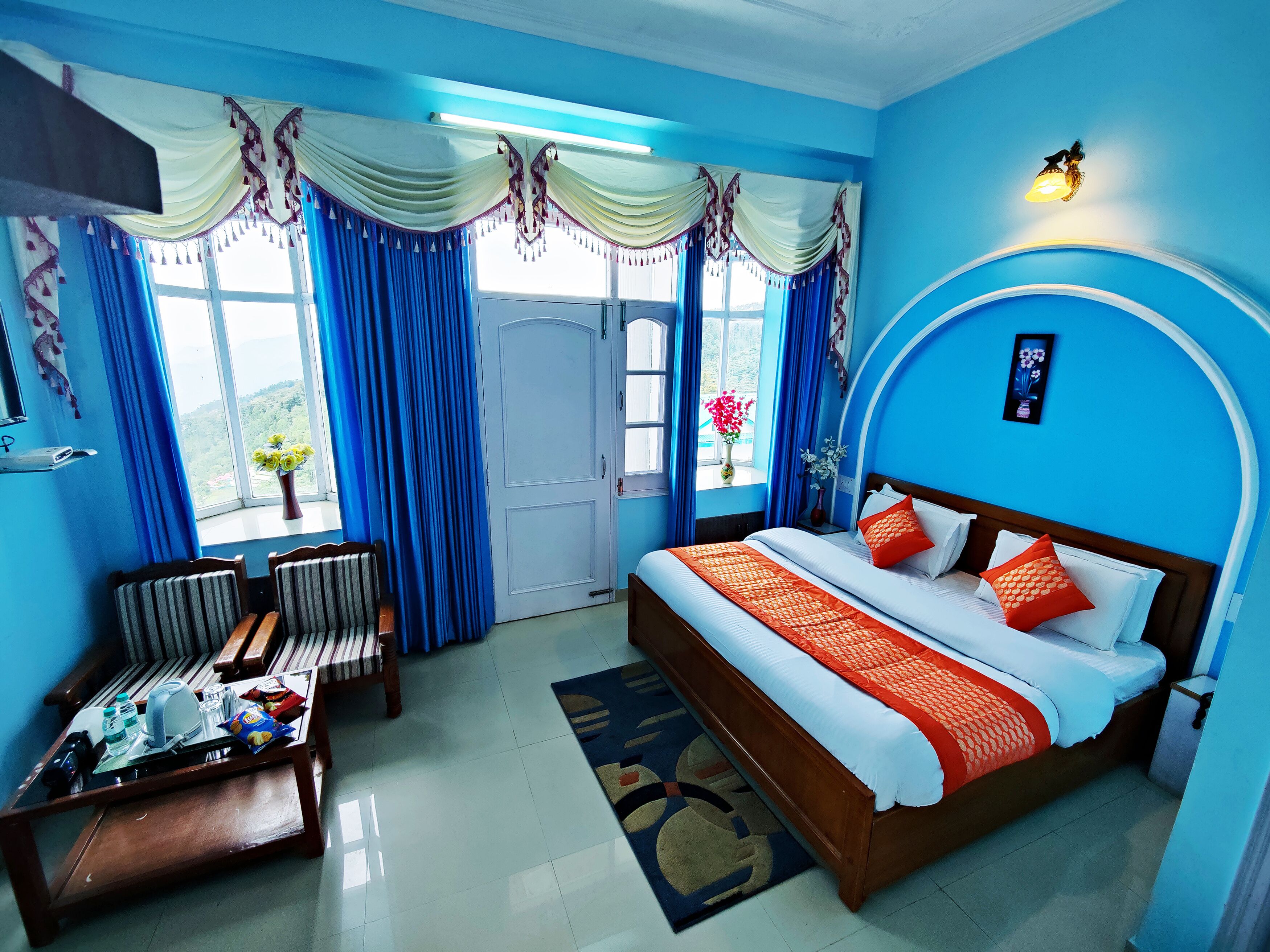 Habitación de hotel con cama, escritorio, sillas y vistas al exterior.