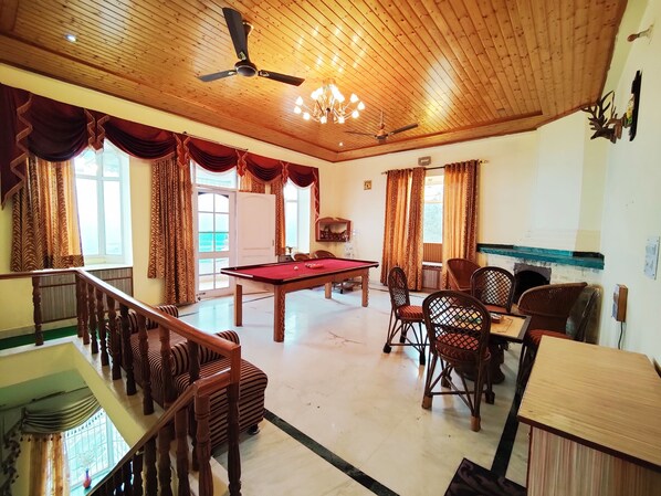 A spacious room with a pool table, comfortable seating, and a ceiling fan.