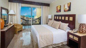 A hotel room with a bed, a desk, a chair, a balcony with a view of the ocean, and artwork on the wall. - Cancun 5 stars Luxury Resort and Spa, 1 bedroom suite, 2 baths, sleep 4 (Punta Sam)