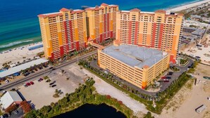Un gran complejo hotelero con múltiples edificios altos, un patio central y ubicación frente a la playa.