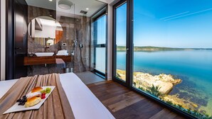 A modern bathroom with a large window overlooking a body of water.