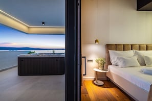 Et moderne soveværelse med en stor seng, et sengebord med lampe og havudsigt.