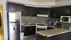 A modern kitchen with black cabinets, a stainless steel refrigerator, a gas stove, and a microwave.