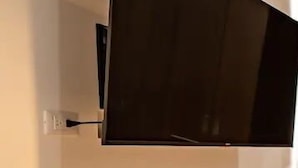 A wall-mounted television in a room with a plain wall, a power outlet, and a wooden floor. - CONDO MR BY TRVL2HM (Puerto Vallarta)