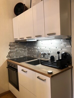 Compact kitchen with a sleek stovetop, oven, and stainless steel sink.
