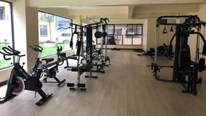 A spacious gym with cardio machines, weightlifting equipment, and large windows offering views of the outside. - DALM-D Cozy lovely studio with Gym in Kileleshwa (Nairobi)