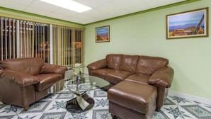 A room with two brown leather sofas, a glass coffee table, and patterned floor tiles. - Ashland Studio Inn By OYO Richmond North near Kings Dominion (Ashland)
