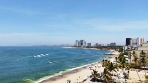 A coastal cityscape with a beach, palm trees, and high-rise buildings.