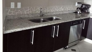 A modern kitchen with dark cabinets, a granite countertop, a stainless steel sink, a microwave, and a dishwasher.