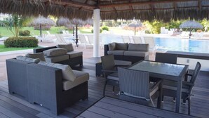 An outdoor lounge area with wicker furniture, a pool, and thatched umbrellas. - CONDO SHAGUI BY TRVL2HM (Puerto Vallarta)