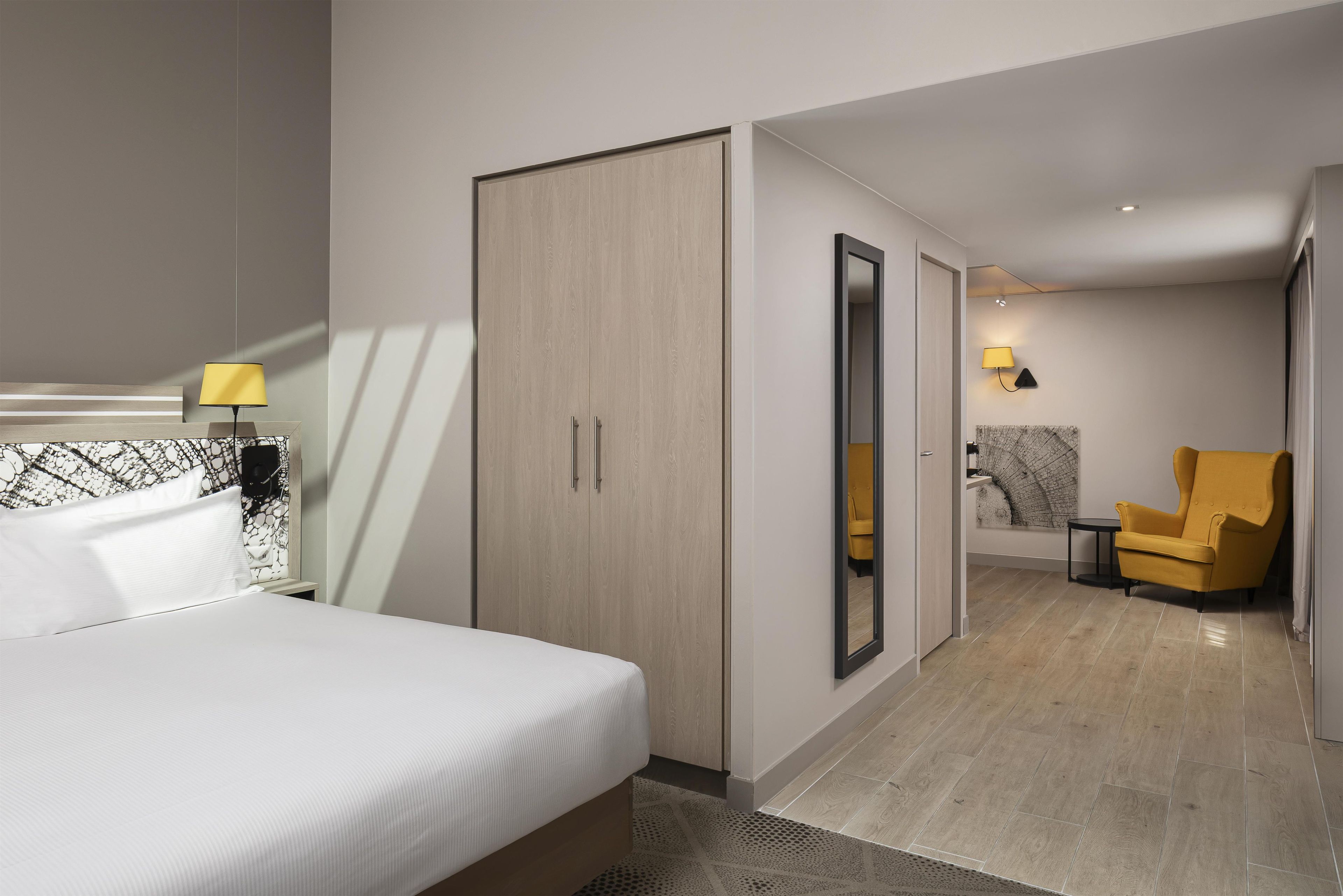 Une chambre d’hôtel comprenant un lit, une armoire, un miroir, une chaise et une petite table.