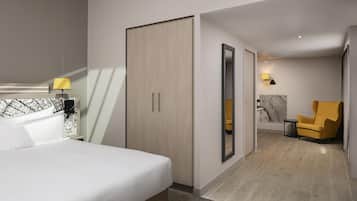 Une chambre d’hôtel comprenant un lit, une armoire, un miroir, une chaise et une petite table.