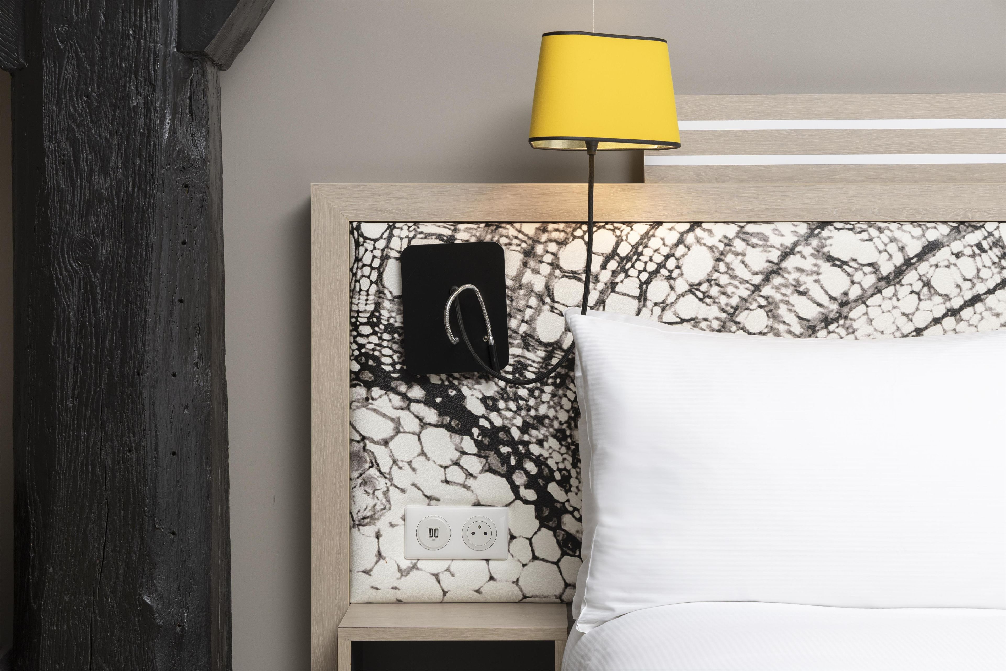 A bed with a white pillow and a headboard with a black and white abstract pattern.