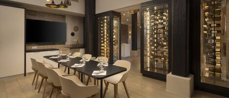 A modern dining area with a long table, chairs, and pendant lighting.
