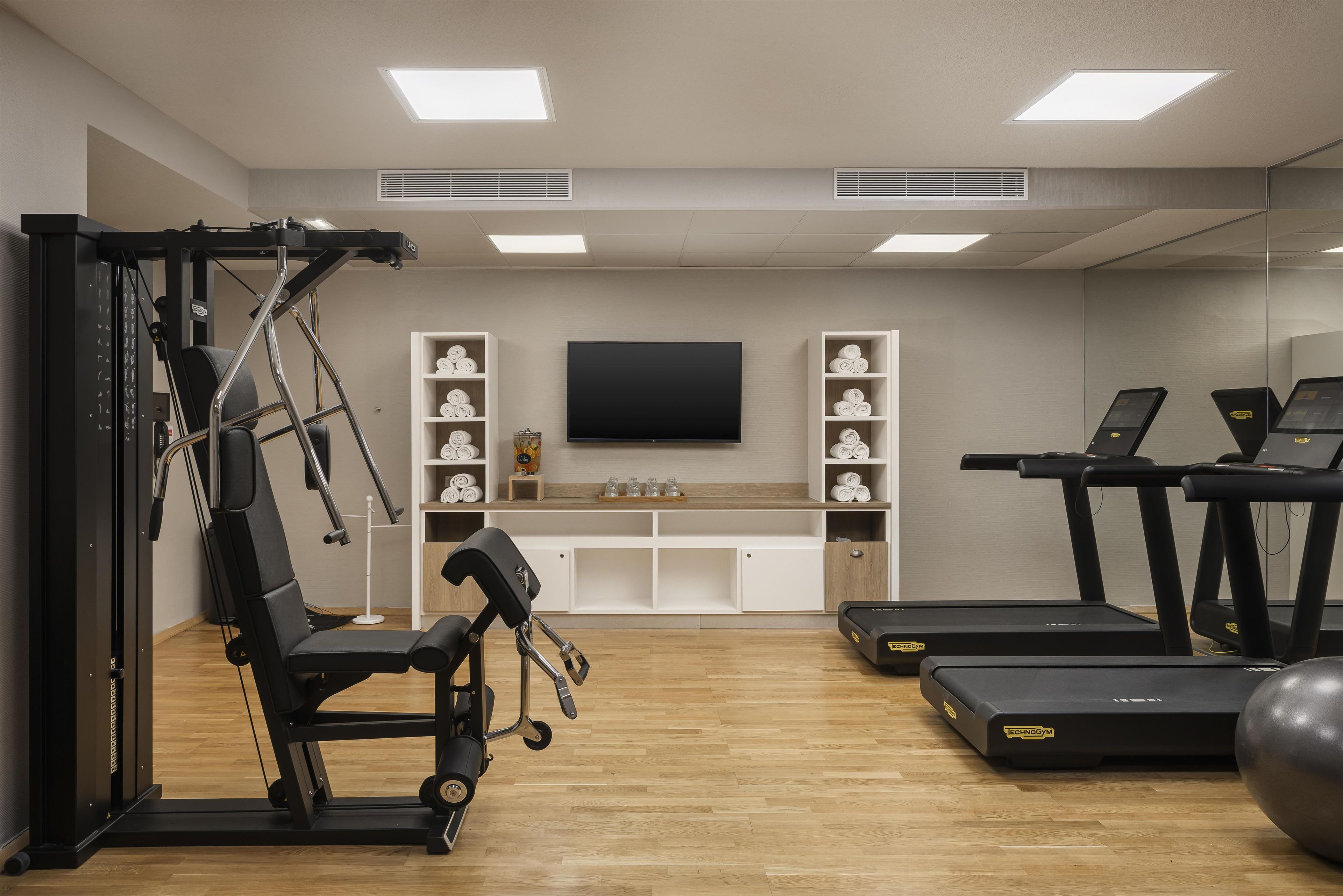 Une salle de sport équipée de matériel d’exercice, d’un téléviseur et d’étagères de rangement.