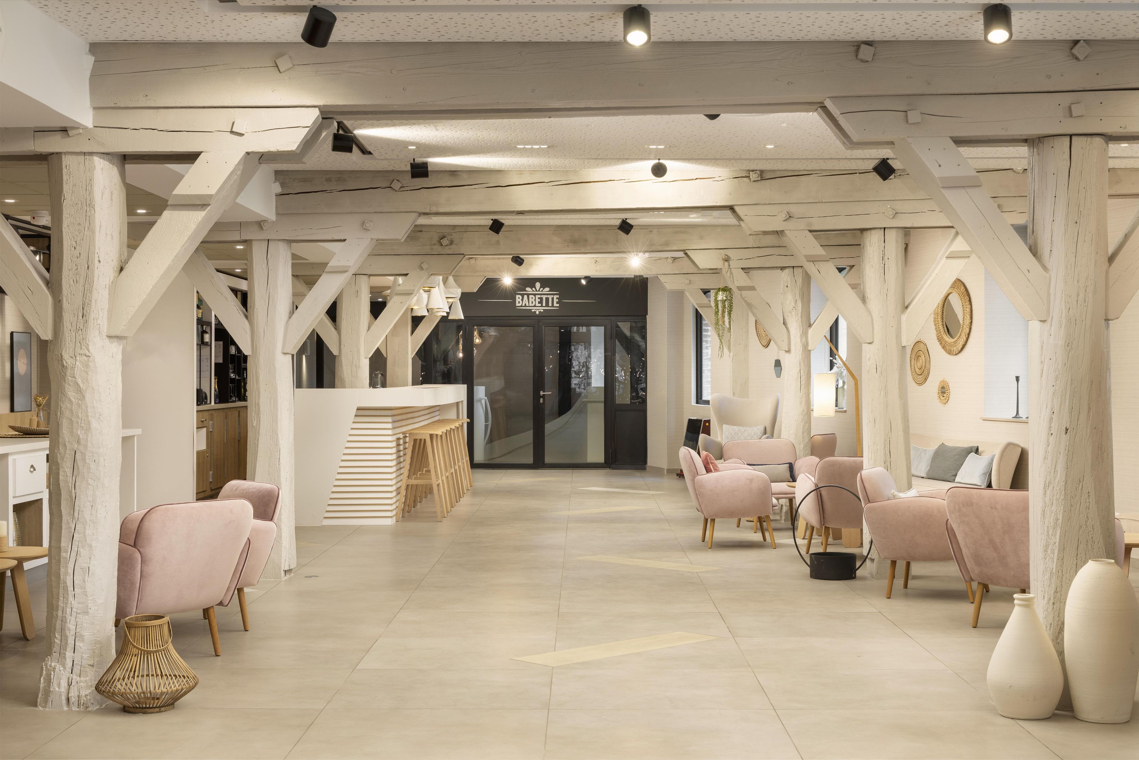 A modern interior with a central bar area, seating arrangements, and a staircase leading to an upper level.