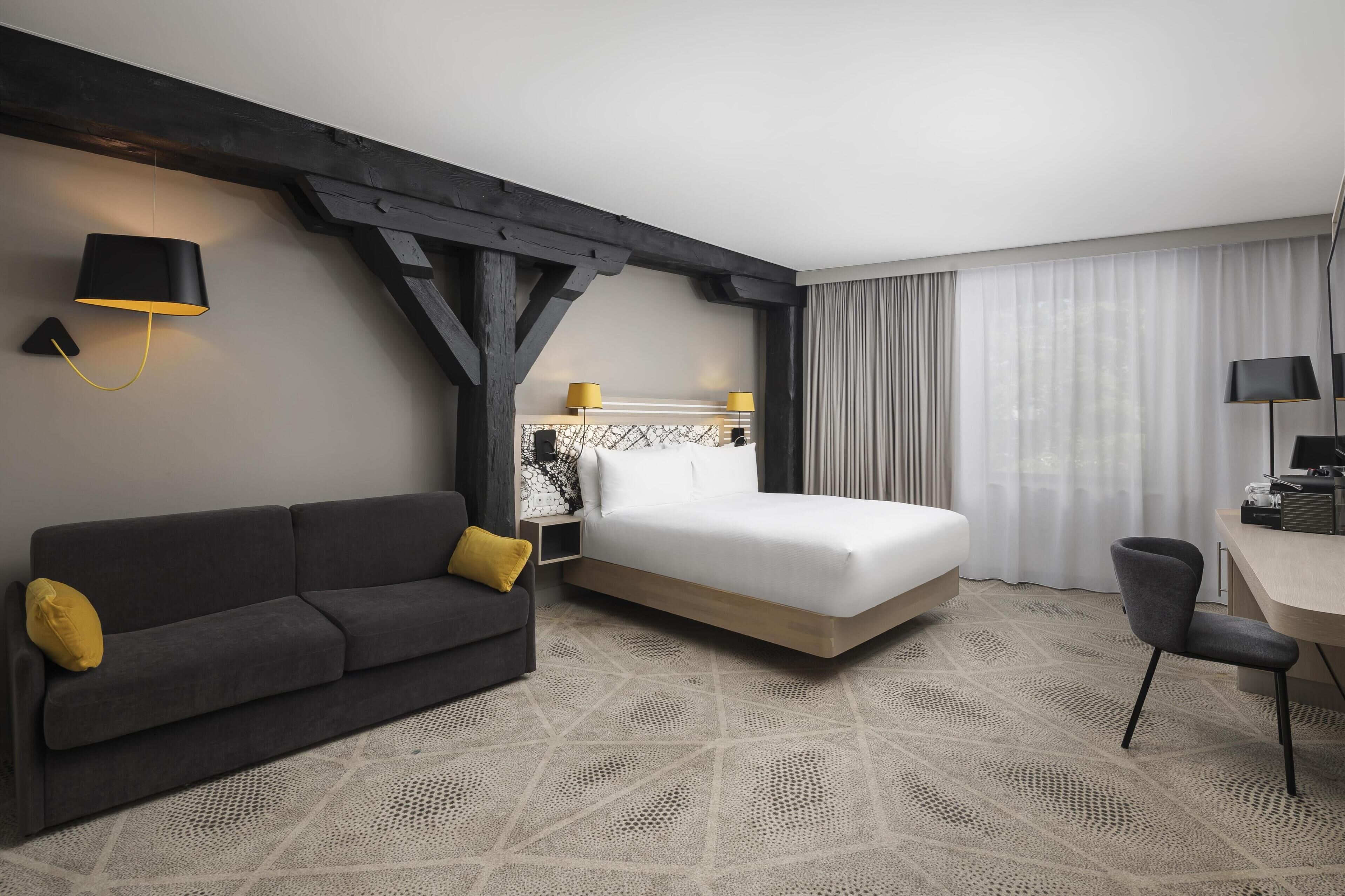 Une chambre d’hôtel moderne équipée d’un lit, d’un canapé, d’un bureau et d’une lampe.