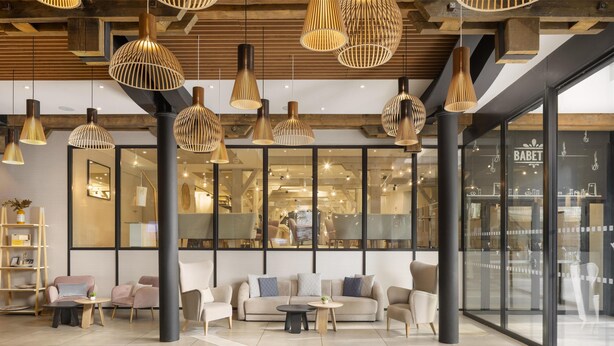 Een modern interieur met een zithoek, ronde tafels en hangende lampen.
