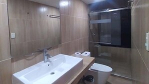 Een moderne badkamer met een groot wastafelmeubel, toilet en een douchecabine van glas.