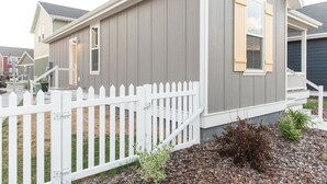 Een woonhuis met een witte picket fence, een grijze gevel en een klein voortuintje.