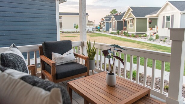 Een houten terras met een stoel en tafel, met uitzicht op een rij herenhuizen.