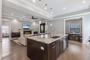 A spacious kitchen with a large island, dark wood cabinets, and a built-in fireplace. - LUXE: Walk to Beach, 2 Kings, Pool & Spa (Naples)