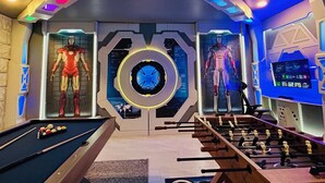 Una habitación con mesa de billar, mesa de fútbolín y dos maniquíes vestidos con trajes de Iron Man.
