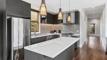 A modern kitchen with a large island, stainless steel appliances, and pendant lighting.