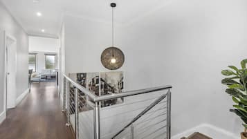 A modern interior with a staircase, a hanging light fixture, and a framed cityscape photo.