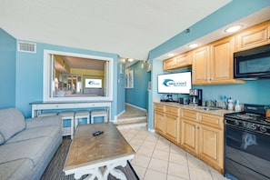 A compact kitchen with wooden cabinets, a microwave, and a stove. - NEW Upscale 1BR Direct Oceanfront with Amazing Views (Myrtle Beach)