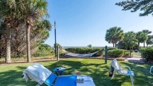 A garden with two lounge chairs, a hammock, and a view of the sea.