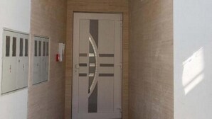 Une entrée d’immeuble avec une porte en verre, un escalier menant à cette porte et une petite fenêtre située au-dessus de la porte.
